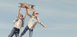 Kids fly cardboard plane outdoors